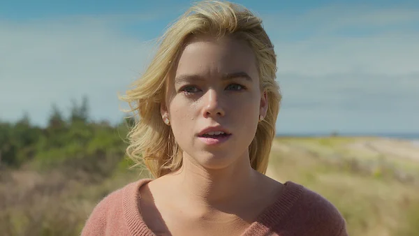 Milly Alcock, interprète de Supergirl, dans un champ herbeux.