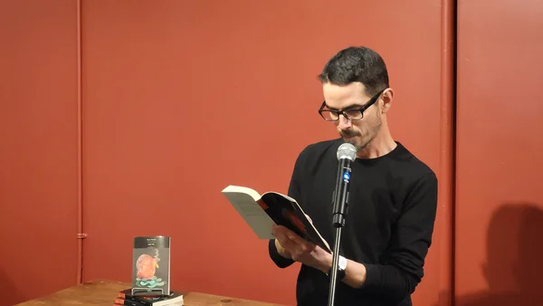 Steve Poutré lisant un extrait de « Lait cru » lors d'une séance de dédicace ou de lecture publique.