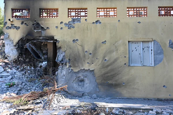 Le kibboutz Be'eri après l'attaque du 7 octobre 2023 : un bâtiment jaune criblé de balles et partiellement effondré.
