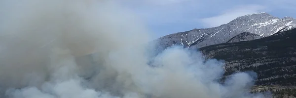 Fumée d'un incendie de forêt s'élevant derrière une chaîne de montagnes dans le sud de la France.