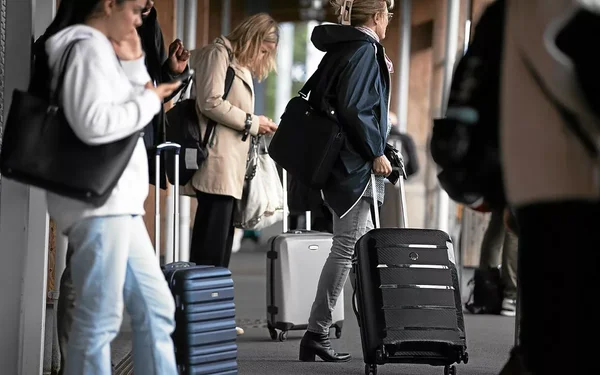Voyageurs faisant la queue sur un quai de gare, prêts pour les départs en vacances.