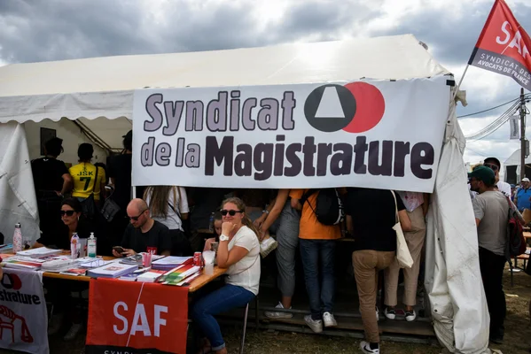 Stand du Syndicat de la magistrature lors d'un événement public, avec banderole et brochures.