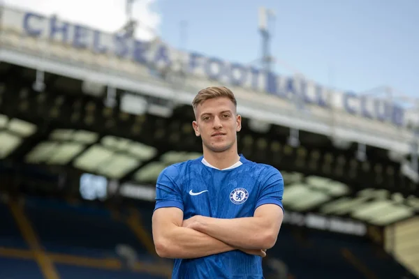 Liam Delap, la nouvelle recrue de Chelsea, pose devant les tribunes de Stamford Bridge.
