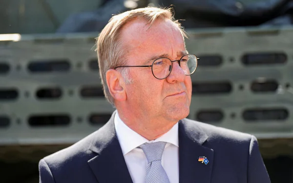 Portrait d'un homme en costume devant un véhicule militaire, illustrant les liens entre l'extrême droite et les fuites d'informations classifiées.