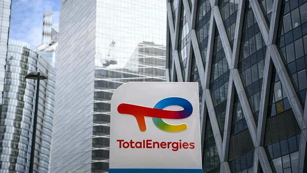 Enseigne de TotalEnergies devant des immeubles modernes.