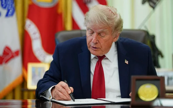 Donald Trump signant un document dans le Bureau ovale de la Maison-Blanche.