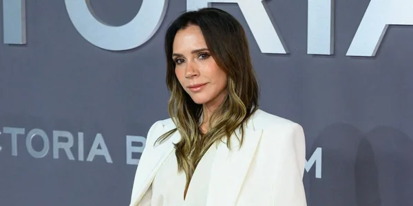 Victoria Beckham posant devant un mur avec des lettres argentées.