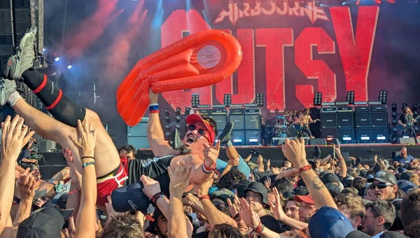 Surfeur de foule avec tube gonflable orange porté par la foule, Airbourne en concert sur scène au Hellfest 2026.