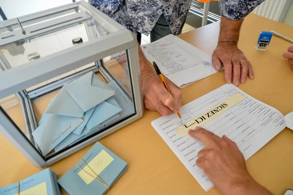 Un électeur signe le registre avant de glisser son enveloppe dans l'urne.