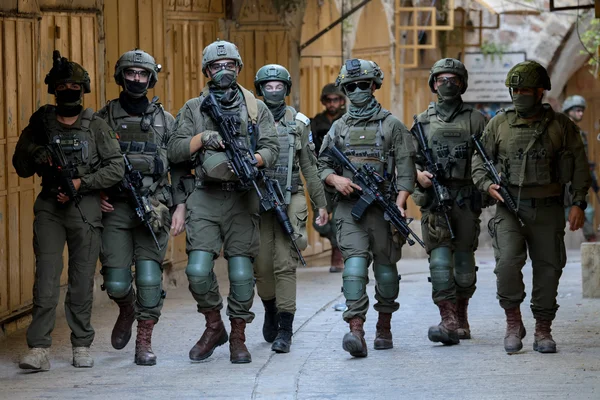 Des soldats israéliens en patrouille dans une zone urbaine, en tenue de combat complète.