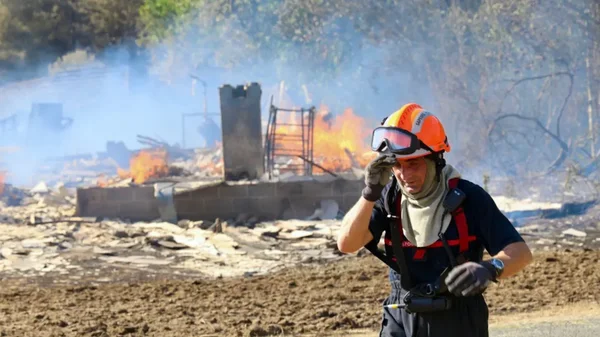 Un pompier s'éloignant d'un bâtiment en feu, témoignant de la dangerosité des interventions.