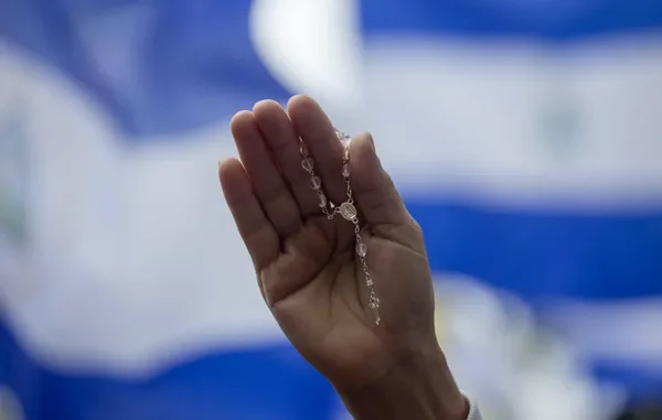 Un chapelet en argent tenu dans une main, symbole religieux dans le contexte de la répression au Nicaragua.