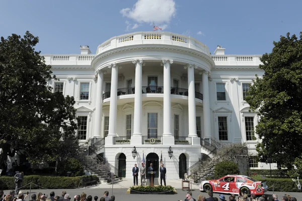 La Maison Blanche avec une voiture de course NASCAR garée devant le portique sud.
