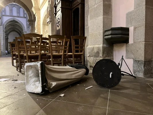 Statue renversée et brisée dans une église, symbole de la violence des dégradations.