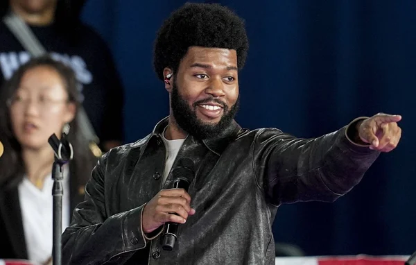 Khalid lors d'un événement, veste en cuir noir et micro en main.