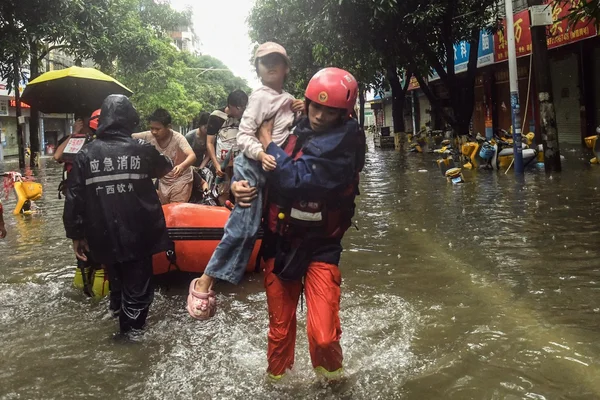 Un secouriste transporte un enfant dans une rue inondée, lors des opérations de secours après les inondations en Chine.
