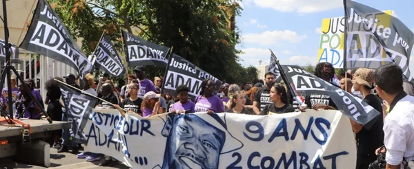 Manifestation pour Adama Traoré, avec la banderole '9 ANS 2 COMBAT' et des drapeaux noirs.
