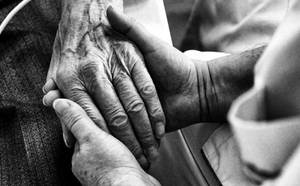 Mains jeunes enserrant une main âgée, en noir et blanc, symbole de tendresse et d'accompagnement.