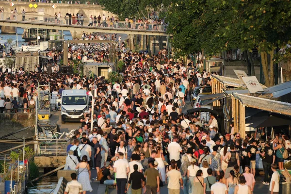Foule nombreuse se déplaçant le long des quais lors de la fête de la musique.