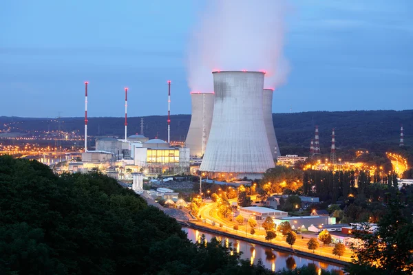 Centrale nucléaire en France au crépuscule, avec tours de refroidissement et cheminées.