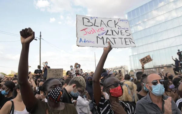 Manifestation massive pour Adama Traoré, avec pancarte 'Black Lives Matter' et poing levé.