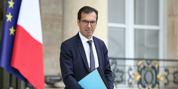 Le ministre du Travail en extérieur, avec les drapeaux français et européen.