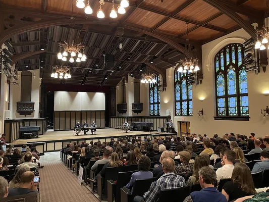 Douglas Wilson (à droite) lors d'un forum public avec des critiques à Idaho, dans une salle aux vitraux.