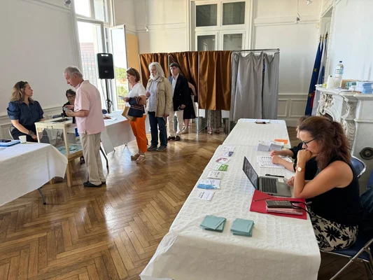 Des électeurs font la queue dans un bureau de vote, prêts à déposer leur bulletin dans l'urne.