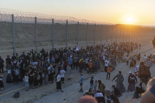 Manifestants israéliens rassemblés près de la clôture de sécurité à la frontière de Gaza au coucher du soleil, réclamant le retour des colonies.