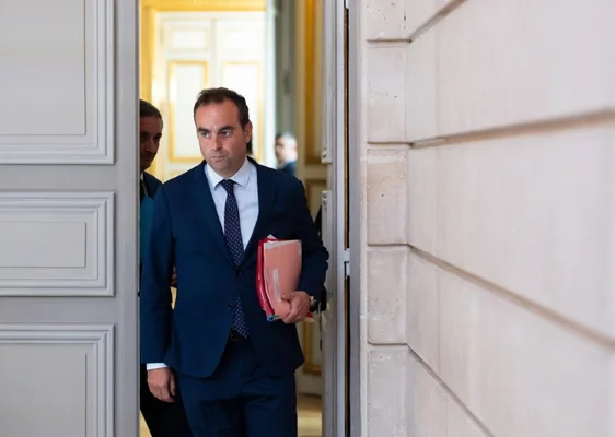 Sébastien Lecornu se déplaçant dans un bâtiment officiel avec des dossiers.