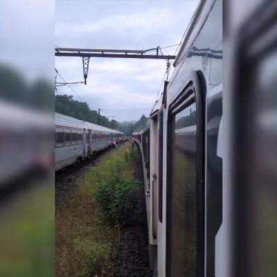 Des voyageurs bloqués entre deux trains sur une voie ferrée, illustrant les retards subis sur la ligne de nuit Paris-Toulouse.