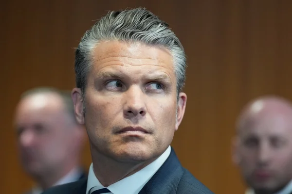 Portrait d'un responsable en costume, le regard tourné, lors d'une conférence ou d'une réunion.