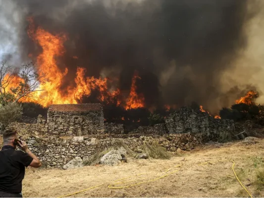 Un incendie majeur ravage plus de 7 000 hectares au Portugal, derrière des ruines et une végétation desséchée.