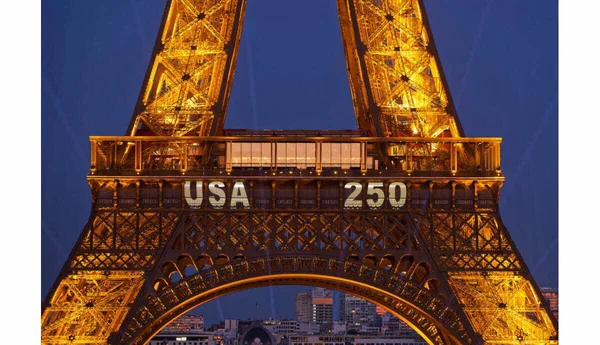 La tour Eiffel illuminée avec la projection 'USA 250' lors de l'escalade d'un homme qui y a accroché un drapeau américain