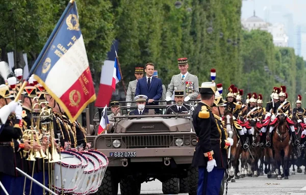 Emmanuel Macron et des officiers militaires passant en revue les troupes lors du défilé du 14 juillet
