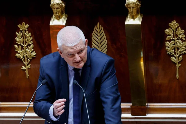 Intervenant au podium devant un mur en boiserie dorée
