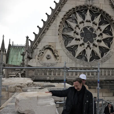 Stéphane Bern sur le chantier de la basilique de Saint-Denis, touchant une pierre devant la façade gothique.