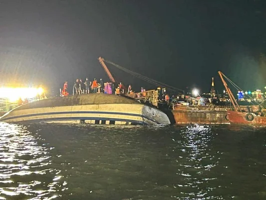 Épave d'un bateau touristique en baie d'Halong, entourée de secouristes.