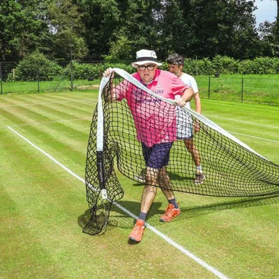 Deux hommes transportant un filet de tennis sur l'un des rares courts en gazon de France, dans le jardin d'un particulier près de Rennes.