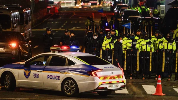 Voiture de police sud-coréenne et policiers anti-émeute lors d'une intervention nocturne à Séoul.