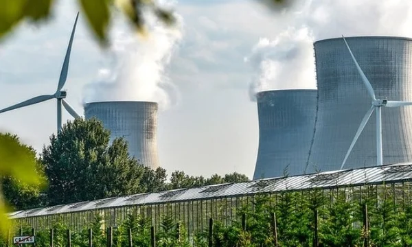Tours de refroidissement d'une centrale nucléaire et éoliennes dans un paysage, symbole de l'électricité bas-carbone.