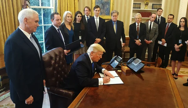 Le président Donald Trump signe les décrets autorisant les pipelines Keystone XL et Dakota Access, entouré de responsables.