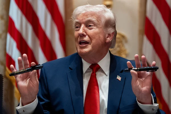 Donald Trump brandissant deux stylos après avoir signé un décret