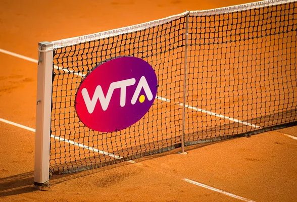 Logo de la WTA sur un filet de tennis en terre battue.