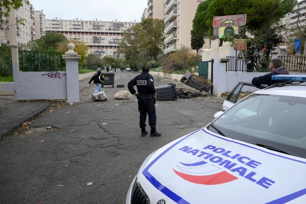 Un policier national sur une rue bloquée par des rochers et des bennes après une fusillade à Marseille.