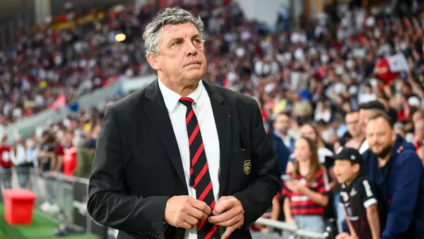Didier Lacroix, président du Stade Toulousain, ajustant sa veste dans un stade.