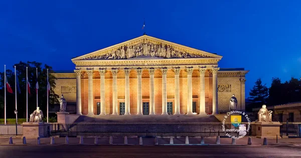 Le Palais Bourbon illuminé de nuit, avec statues et drapeaux.