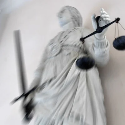 Statue de la Justice, symbole des décisions judiciaires, dans un cadrage flou et dynamique.