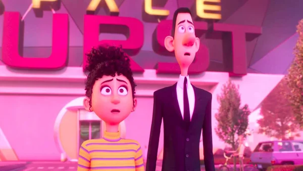 Capture d'écran du film d'animation 'Vice-versa 2' montrant un garçon et un homme en costume noir, choqués devant un bâtiment rose.