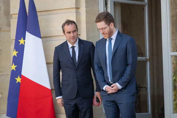 Raphaël Glucksmann devant un bâtiment officiel, aux côtés des drapeaux français et européen.
